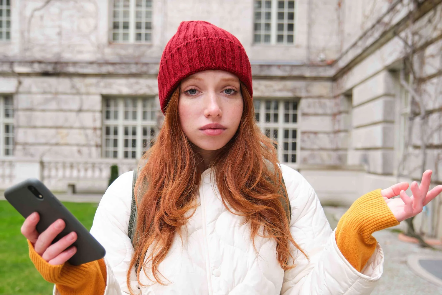 portrait-confused-redhead-girl-with-smartphone-shrugs-shoulders-with-puzzled-clueless-face