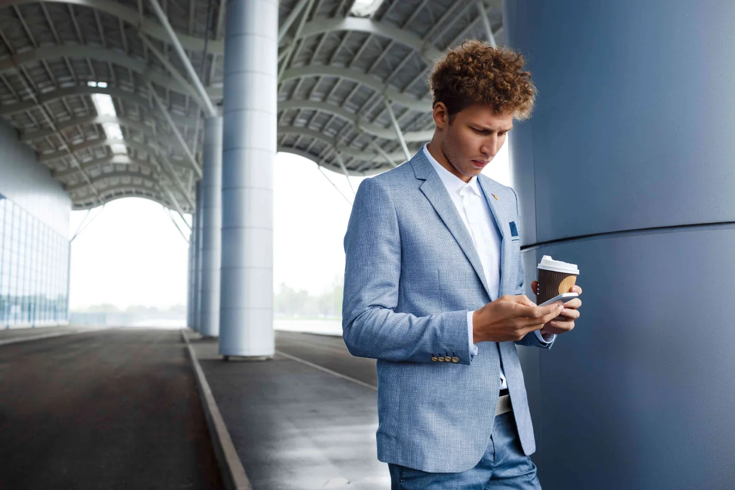 redhaired businessman drinking coffee using phone at airport